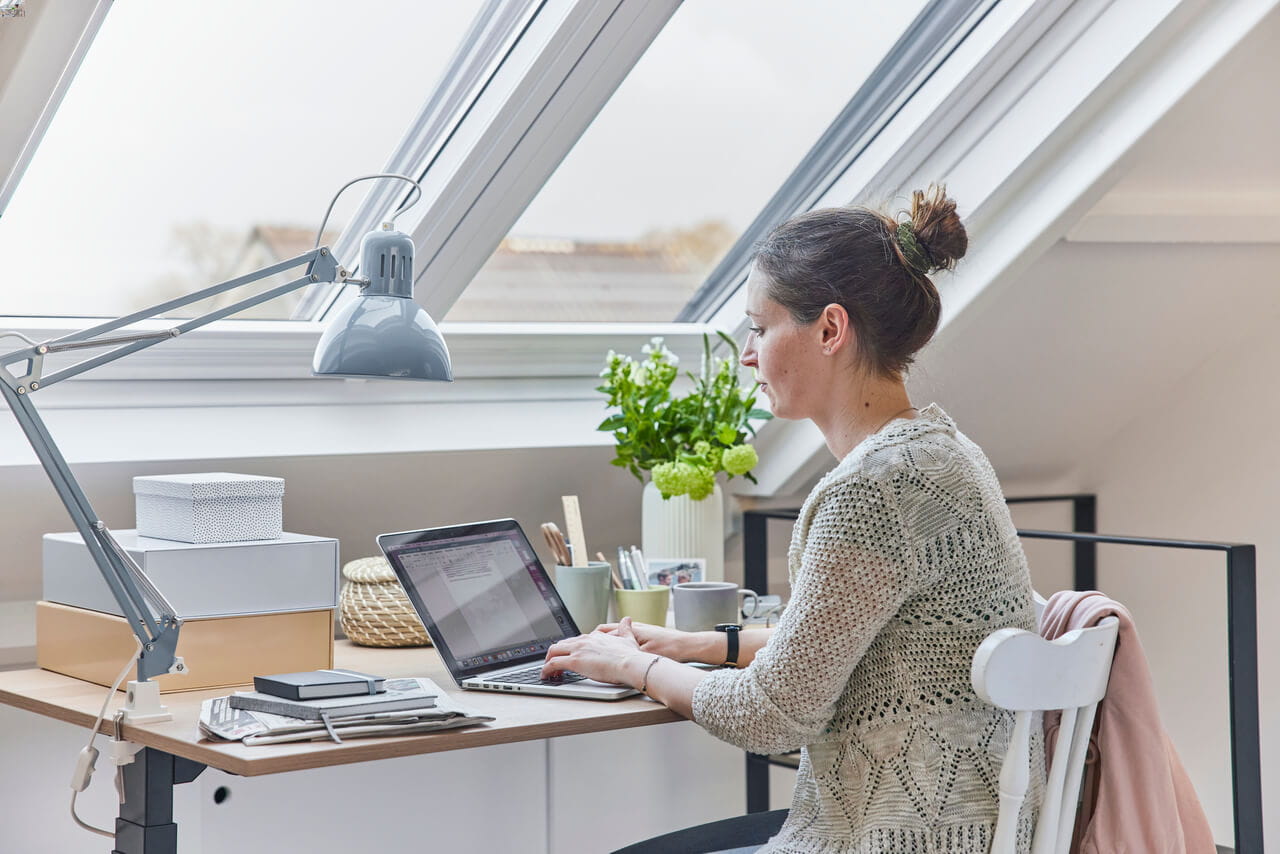 Mysigt kontor på vinden med VELUX takfönster, skrivbord och laptop.