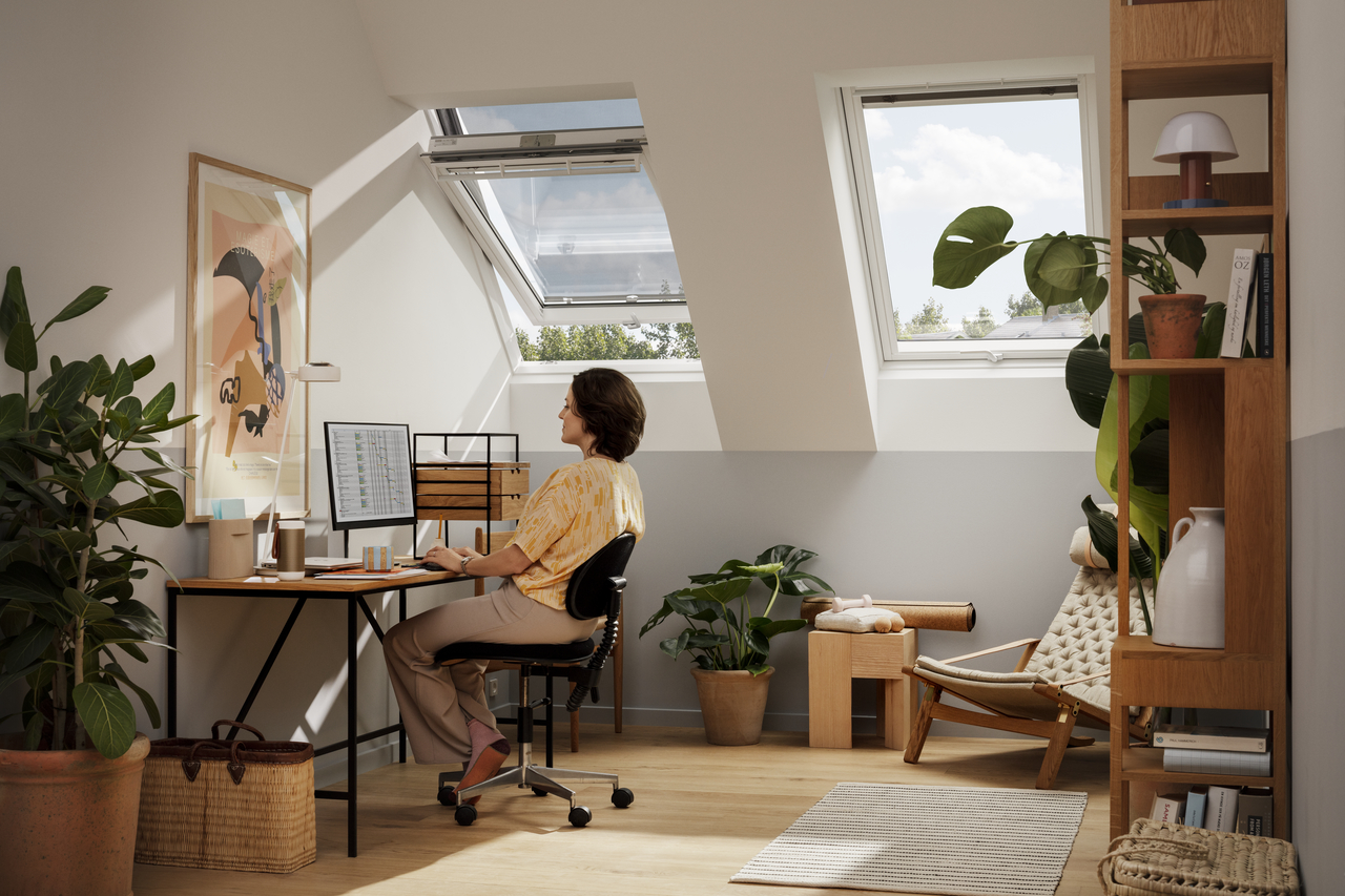 Loft home office with VELUX window, plants, and wooden furniture.