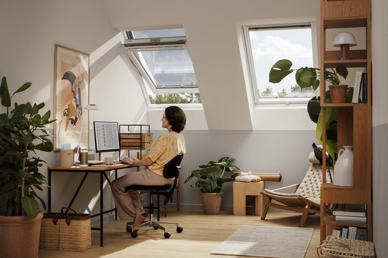 Home office in attic with VELUX window, plants, and wooden furniture.