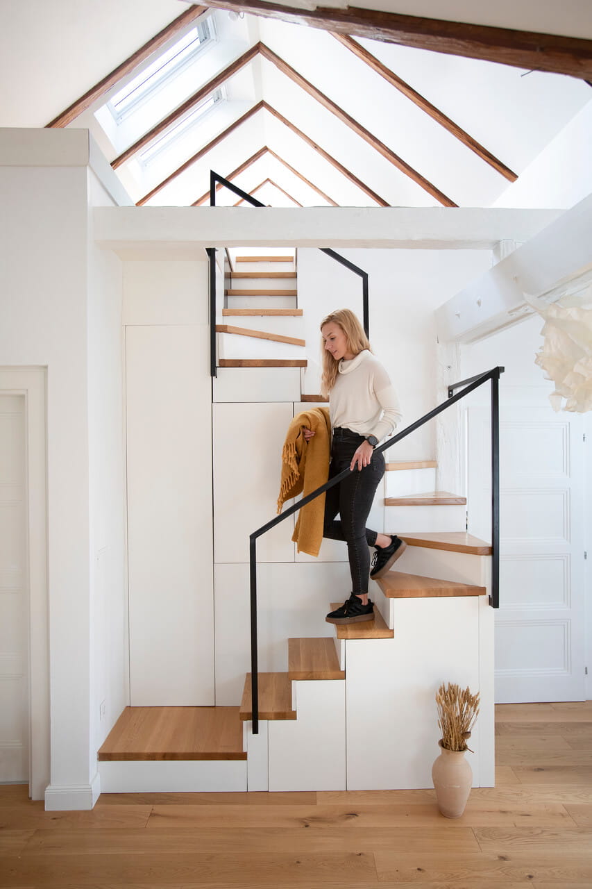 Escalier moderne avec des marches en bois, rangement blanc et fenêtres de toit VELUX.