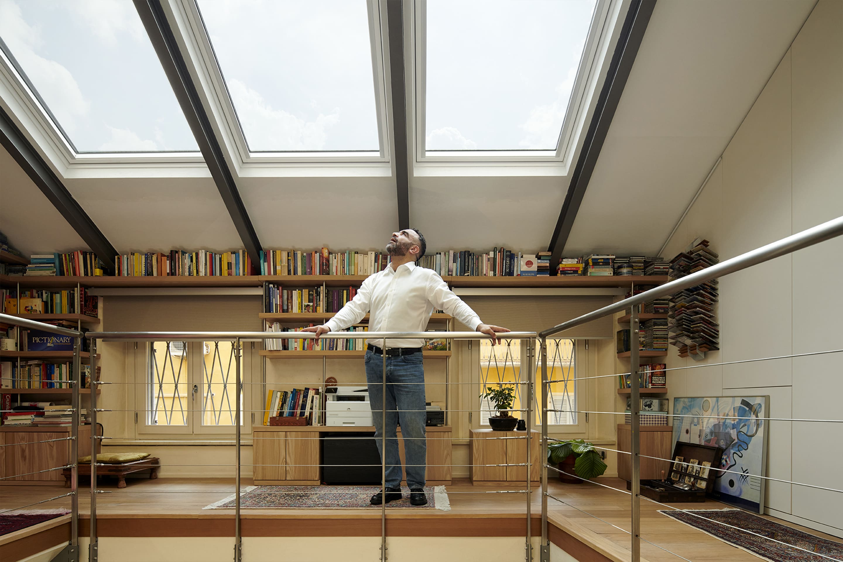 Uomo in ufficio domestico sottotetto con finestre per tetti VELUX e scaffali per libri.