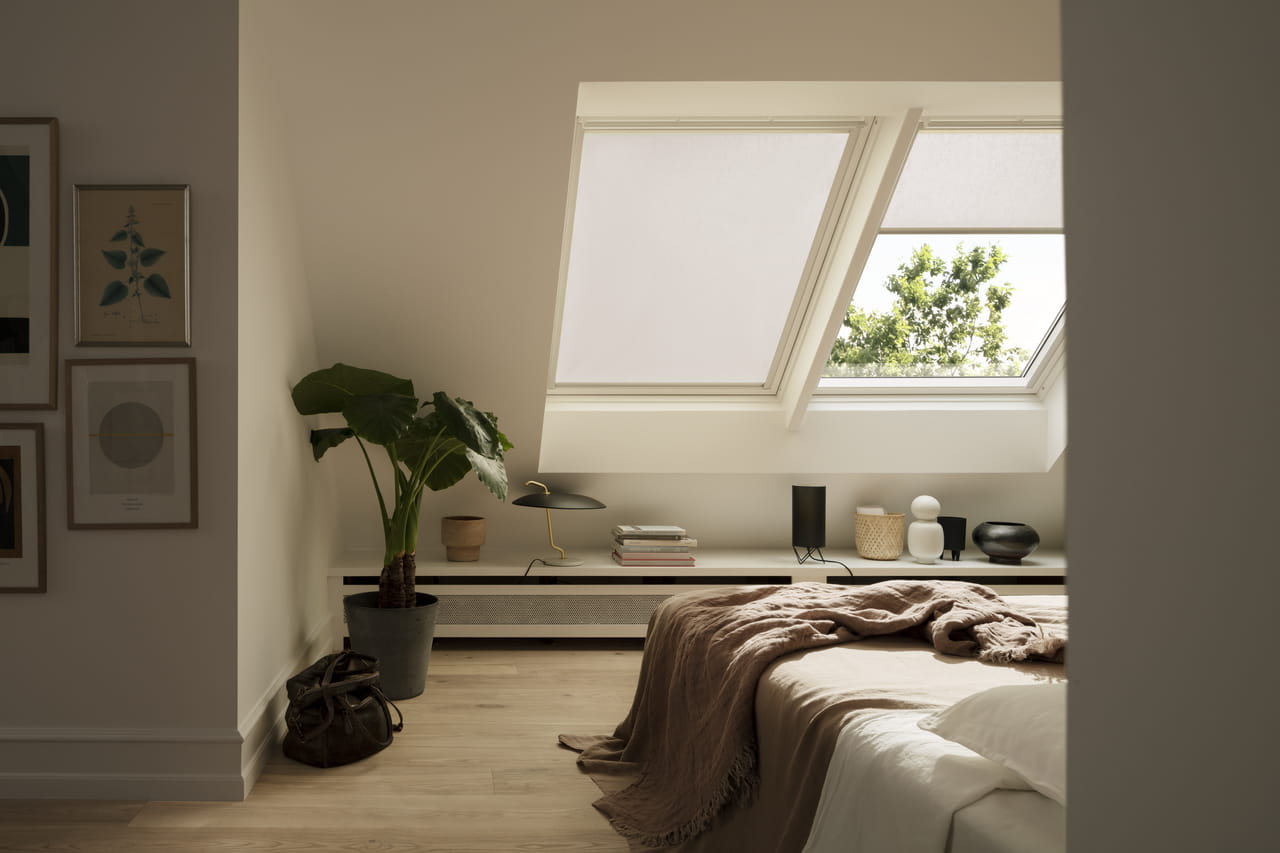 Cosy bedroom with VELUX roof window, bed, plants, and modern decor.