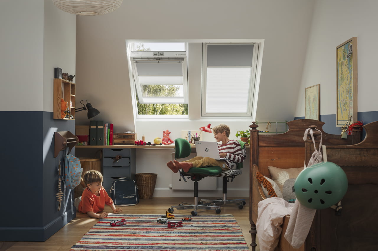 Lyst barnerom med VELUX-vindu, skrivebord, leker på teppet og en tre-seng.