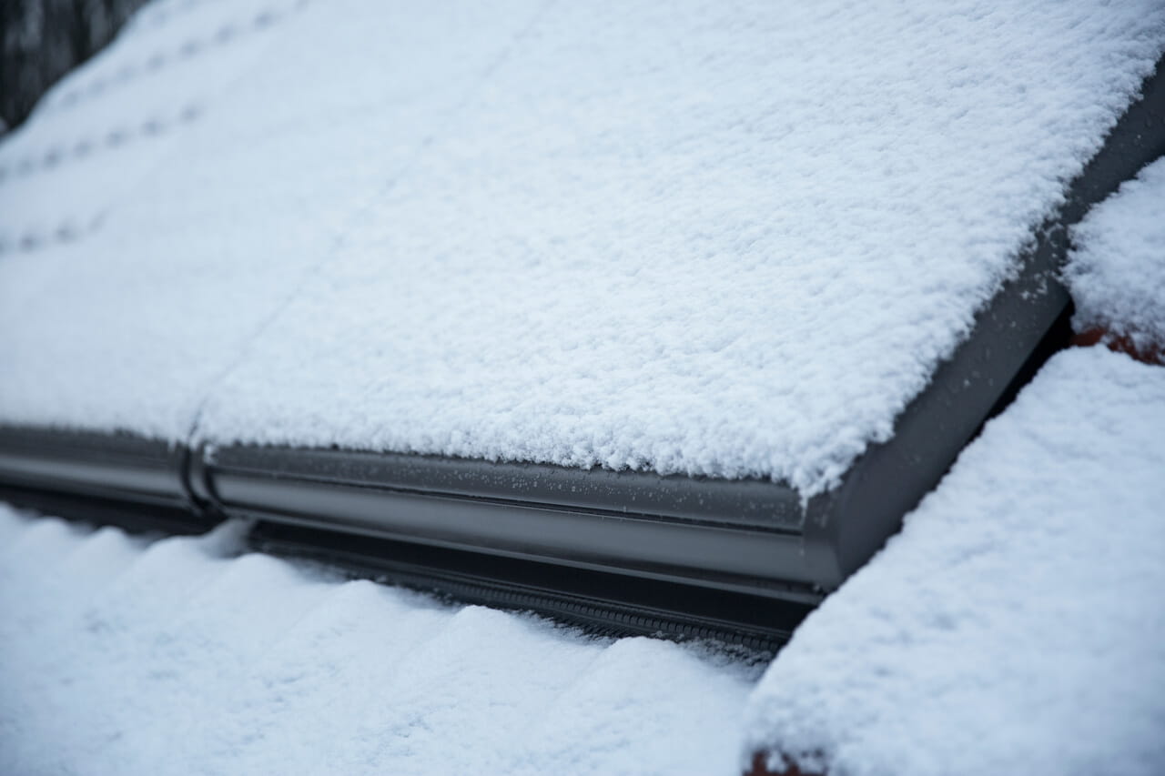Close-up van een VELUX dakvenster bedekt met sneeuw, ter illustratie van de isolatiekwaliteit.