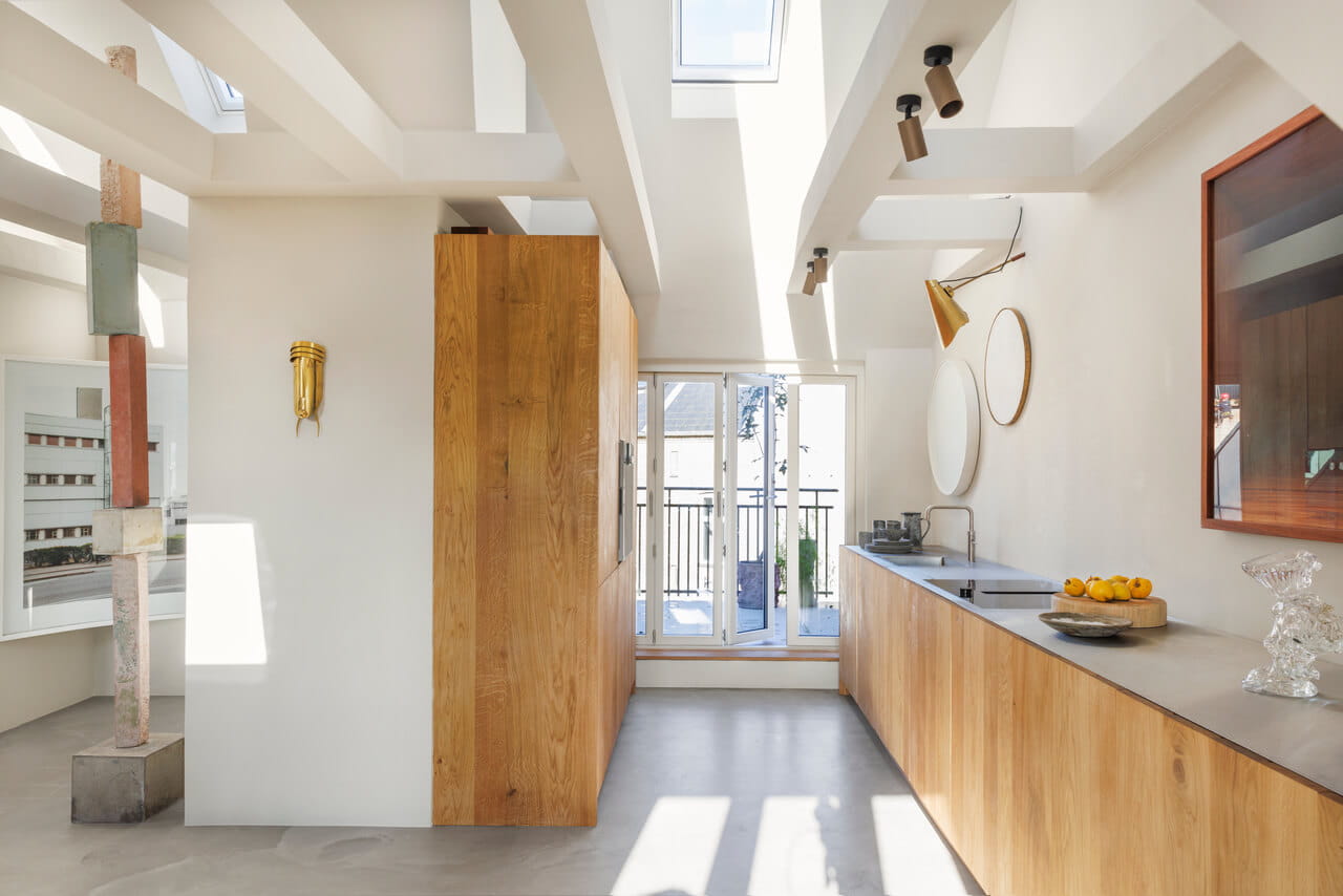 Moderne lichte keuken met VELUX dakvenster en houten kasten die naar het balkon leiden.