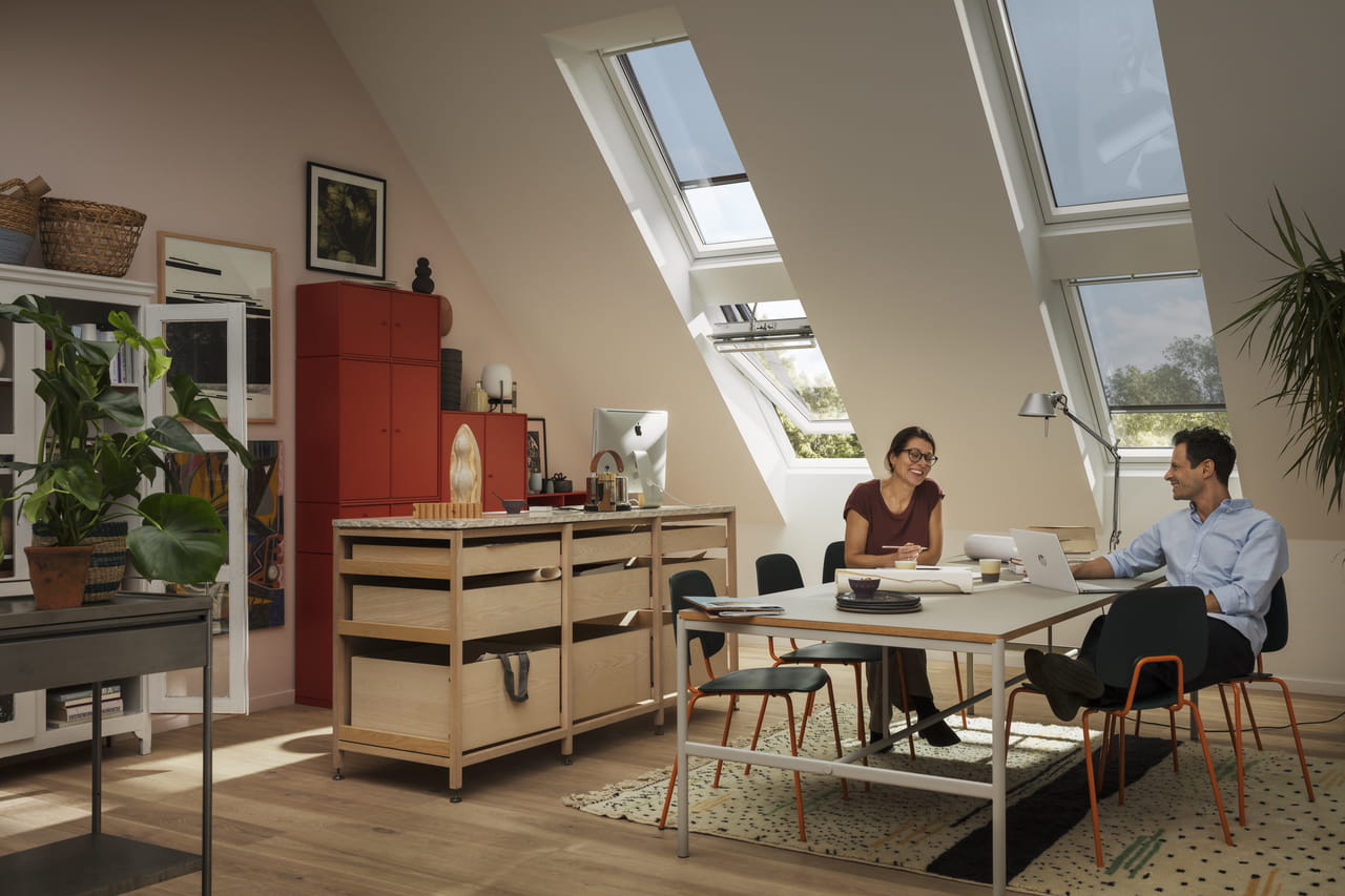 Loft home office with VELUX window, wooden desk, red cupboard, and plants.