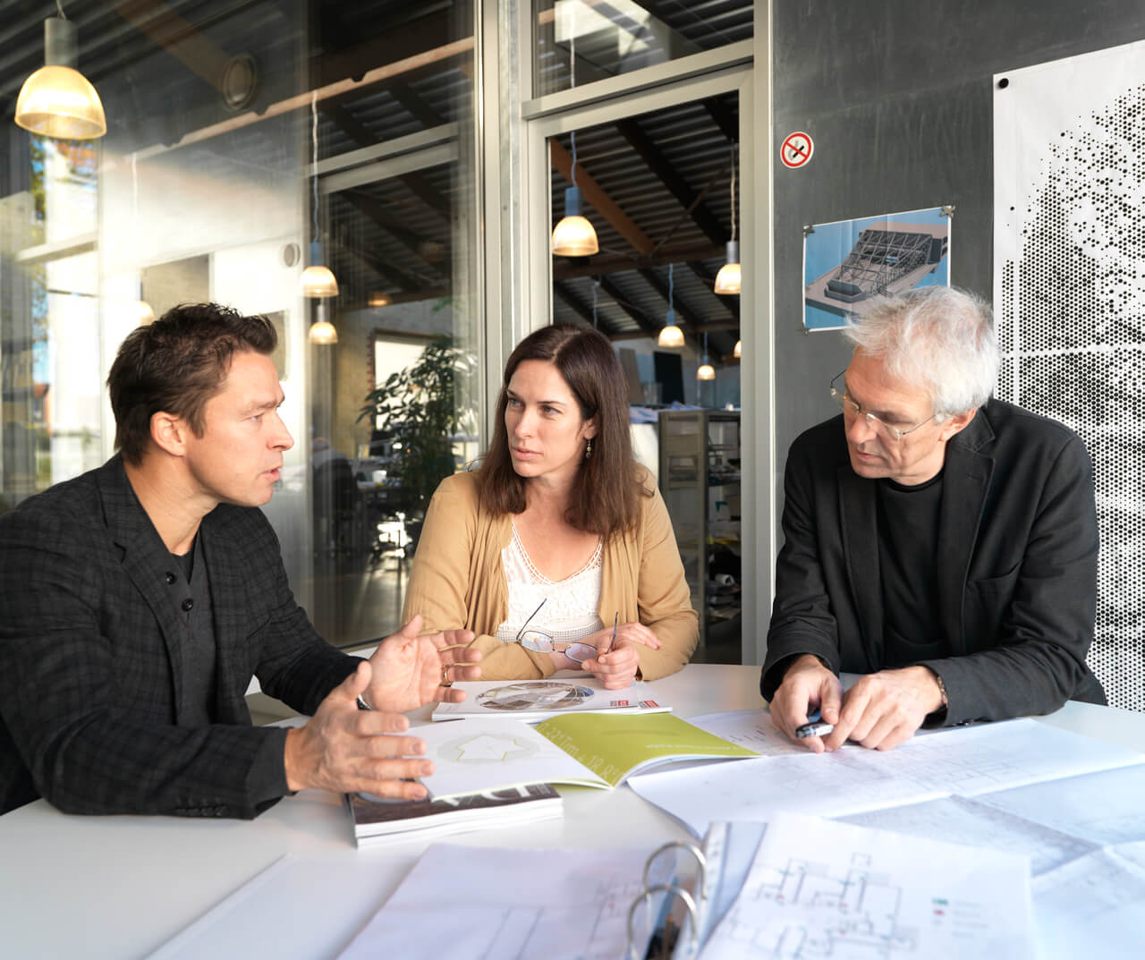 Professionals discussing plans in a modern office with documents on table.