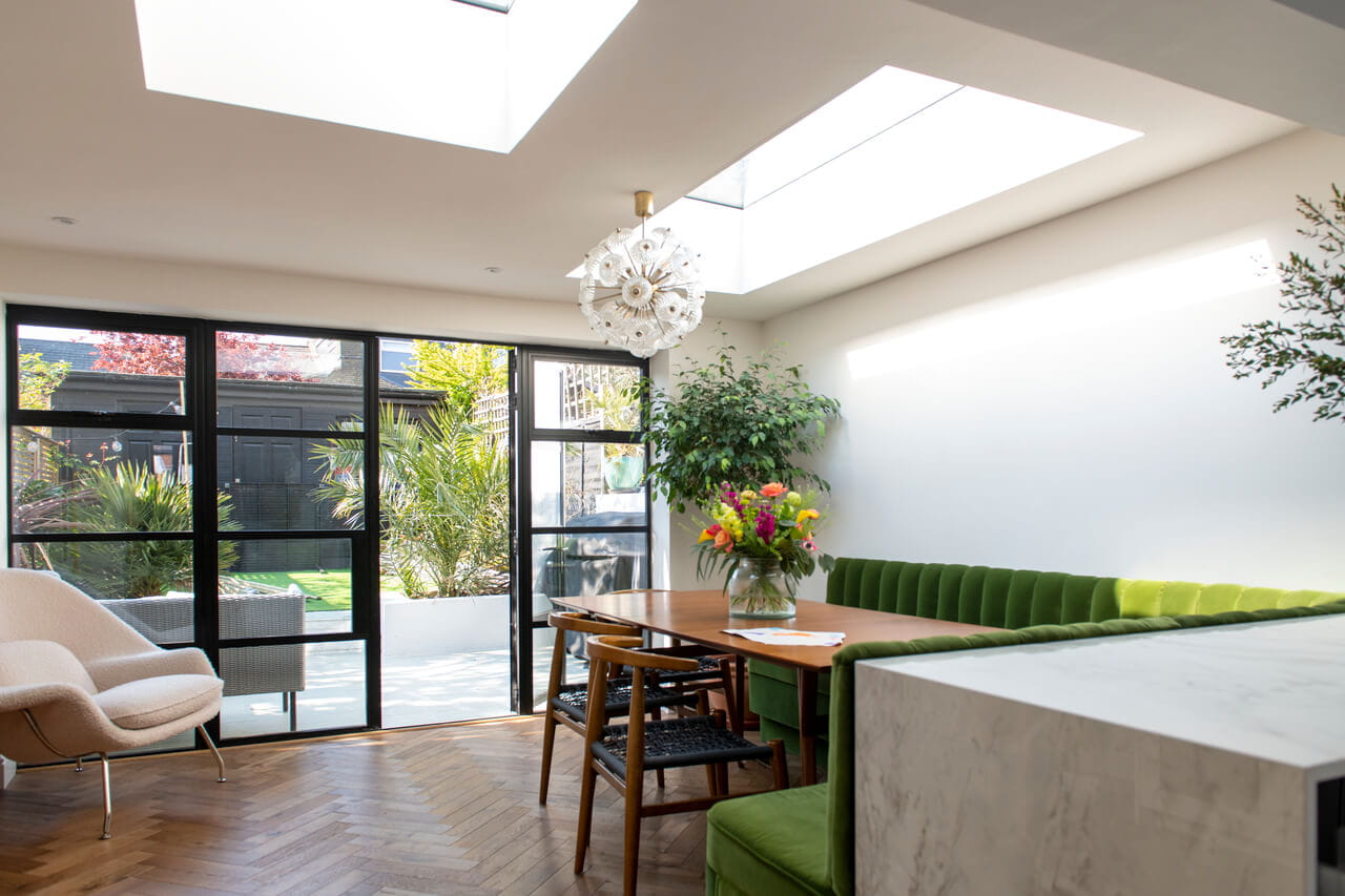 Moderne eetkamer met VELUX dakvensters en tuinweergave door glazen deuren.