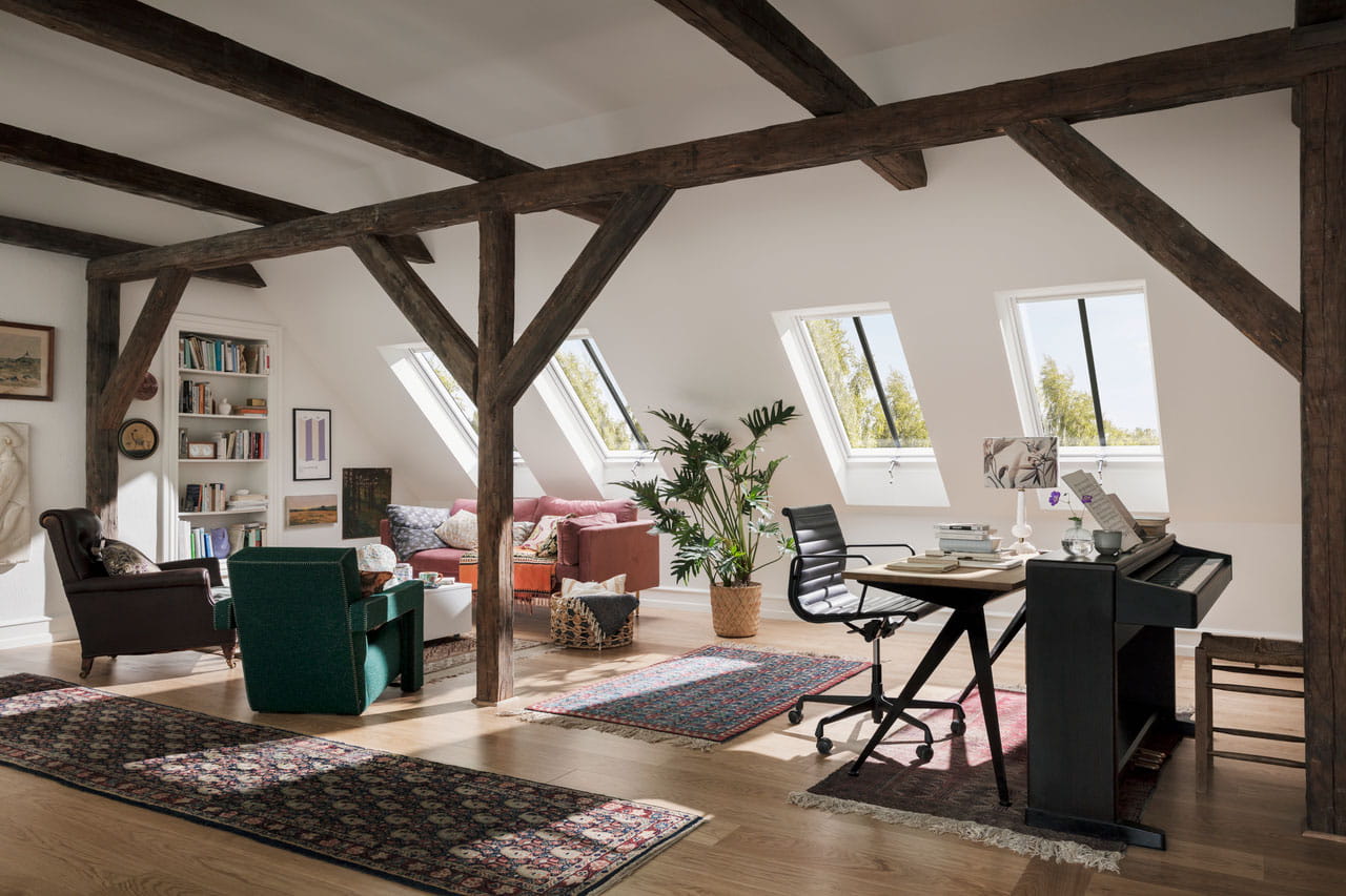 Cosy loft home office with exposed beams and VELUX skylights.