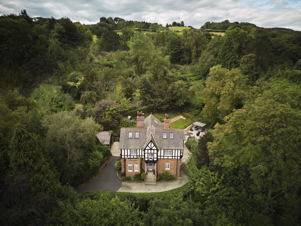 Aerial view of a traditional countryside house surrounded by dense woodland.