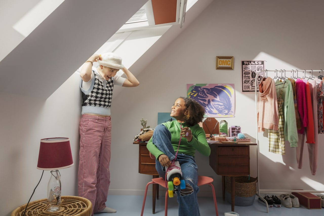 Camera da adolescente con stender per vestiti, finestra VELUX e decorazioni colorate.