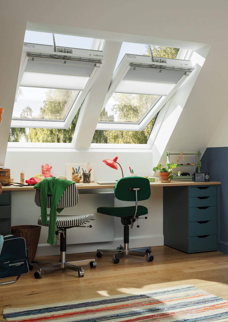 Dachboden-Heimbüro mit natürlichem Licht von VELUX Dachflächenfenstern, Schreibtisch und grünen Stühlen.