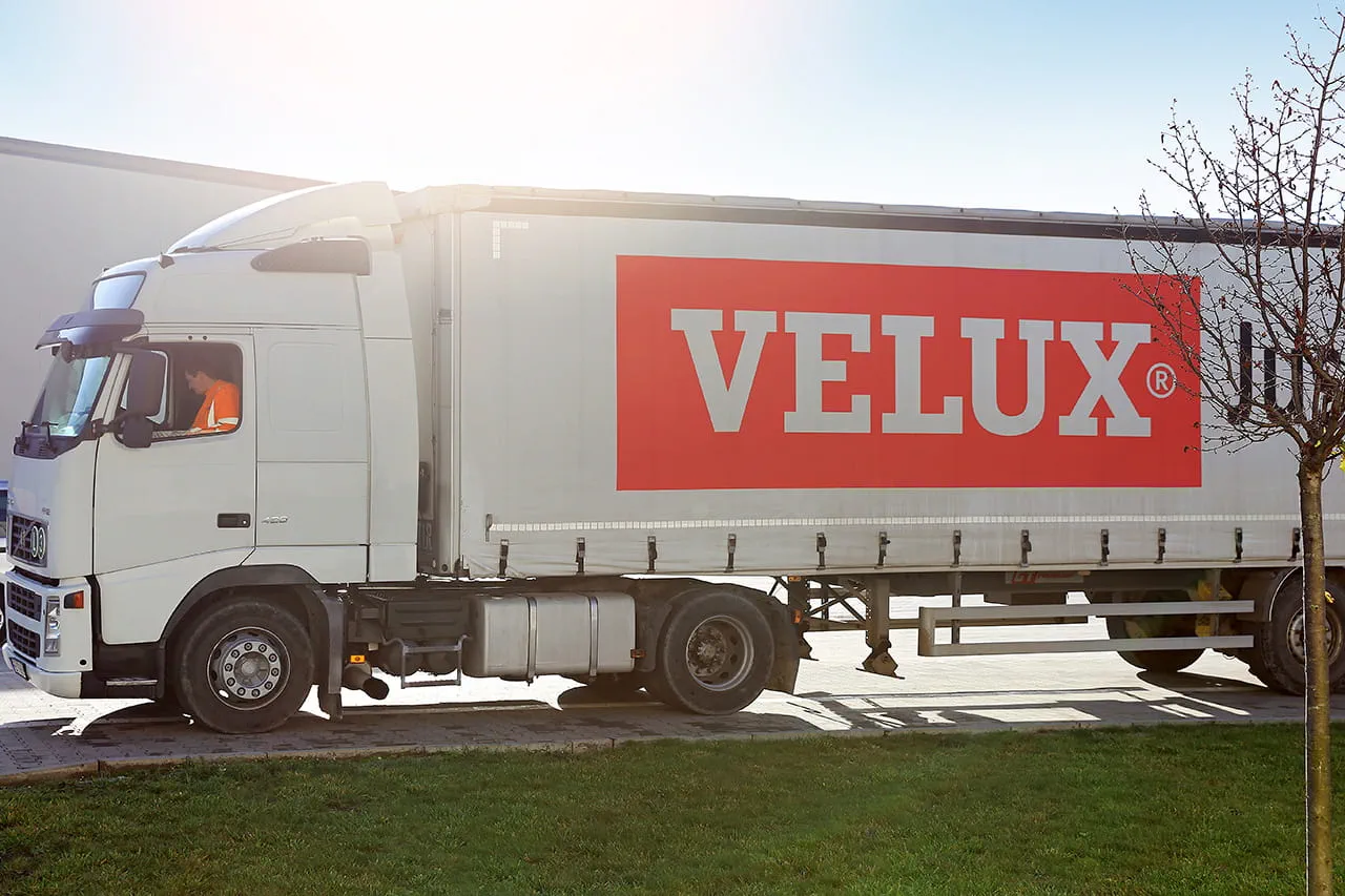 VELUX-Lieferwagen im Sonnenlicht mit sichtbarem Fahrer, der das Markenlogo hervorhebt.