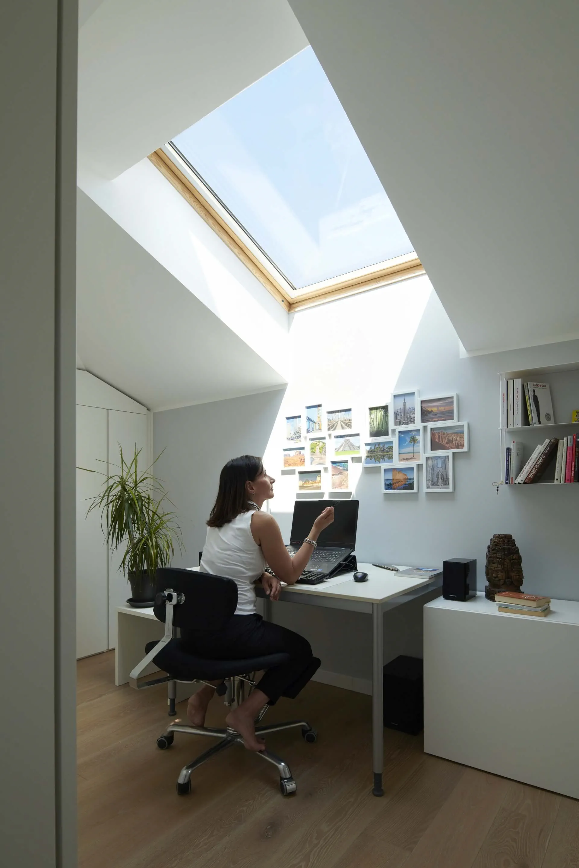 Modernes Homeoffice mit natürlichem Licht von VELUX Dachflächenfenster, Schreibtisch, Stuhl und Wandbildern.