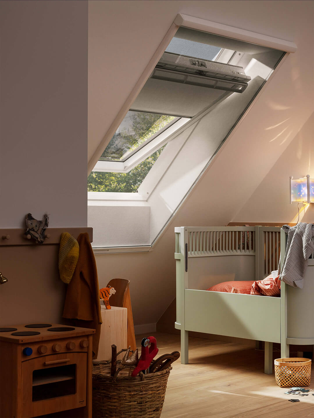 Kinderzimmer mit Bett, Spielzeug und einem VELUX Dachflächenfenster, durch das Sonnenlicht einfällt.
