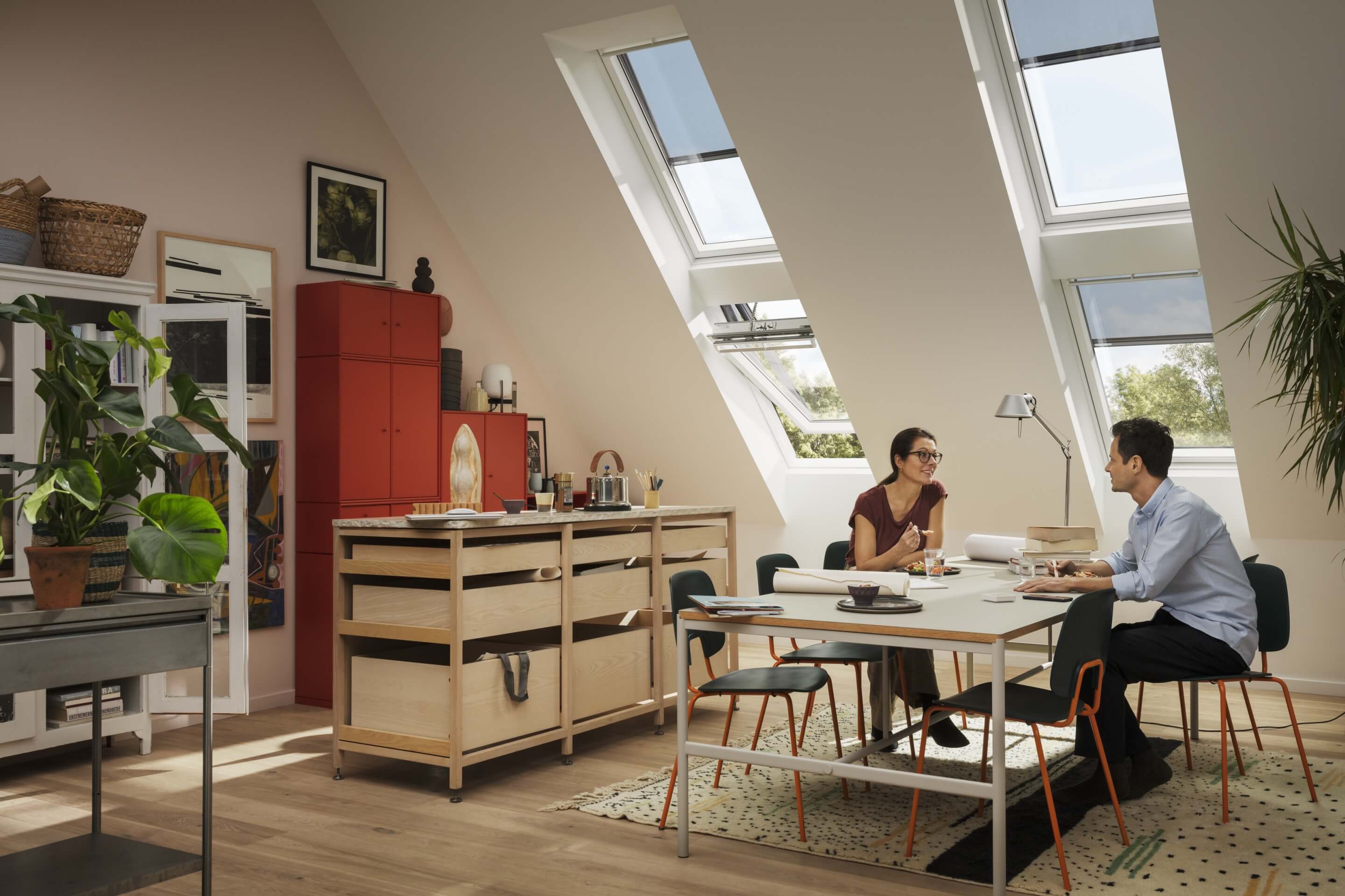 Moderner Dachboden-Esszimmer mit VELUX Dachflächenfenster und rotem Schrank.