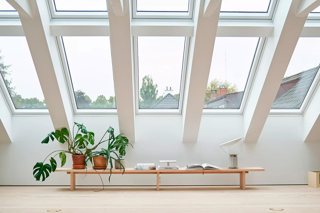 Minimalistisches Home-Office mit VELUX Dachflächenfenstern und Zimmerpflanzen.