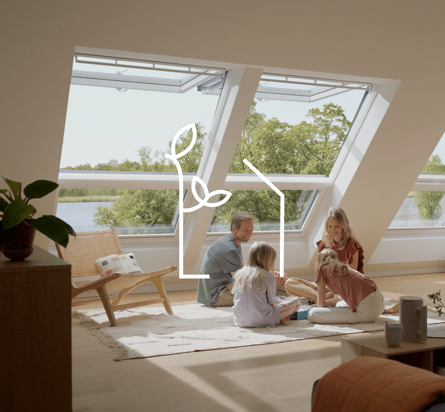 Familie liest auf dem Dachboden in einem Raum mit offenen VELUX Dachflächenfenstern mit Blick auf den Fluss.