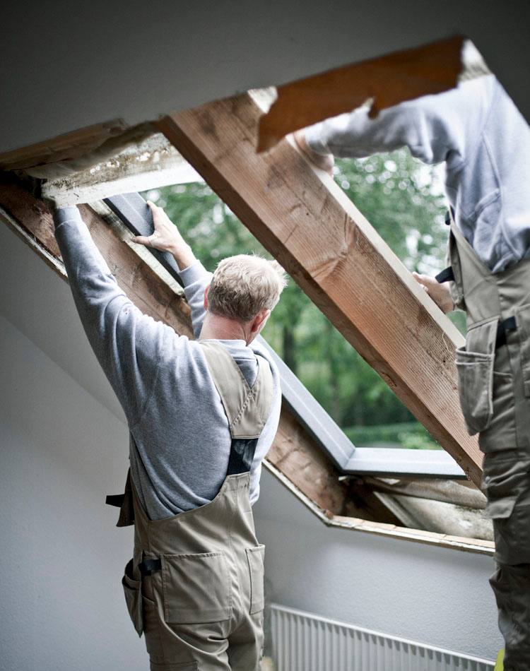 Zwei Arbeiter montieren ein VELUX Dachflächenfenster in eine Schrägdecke.