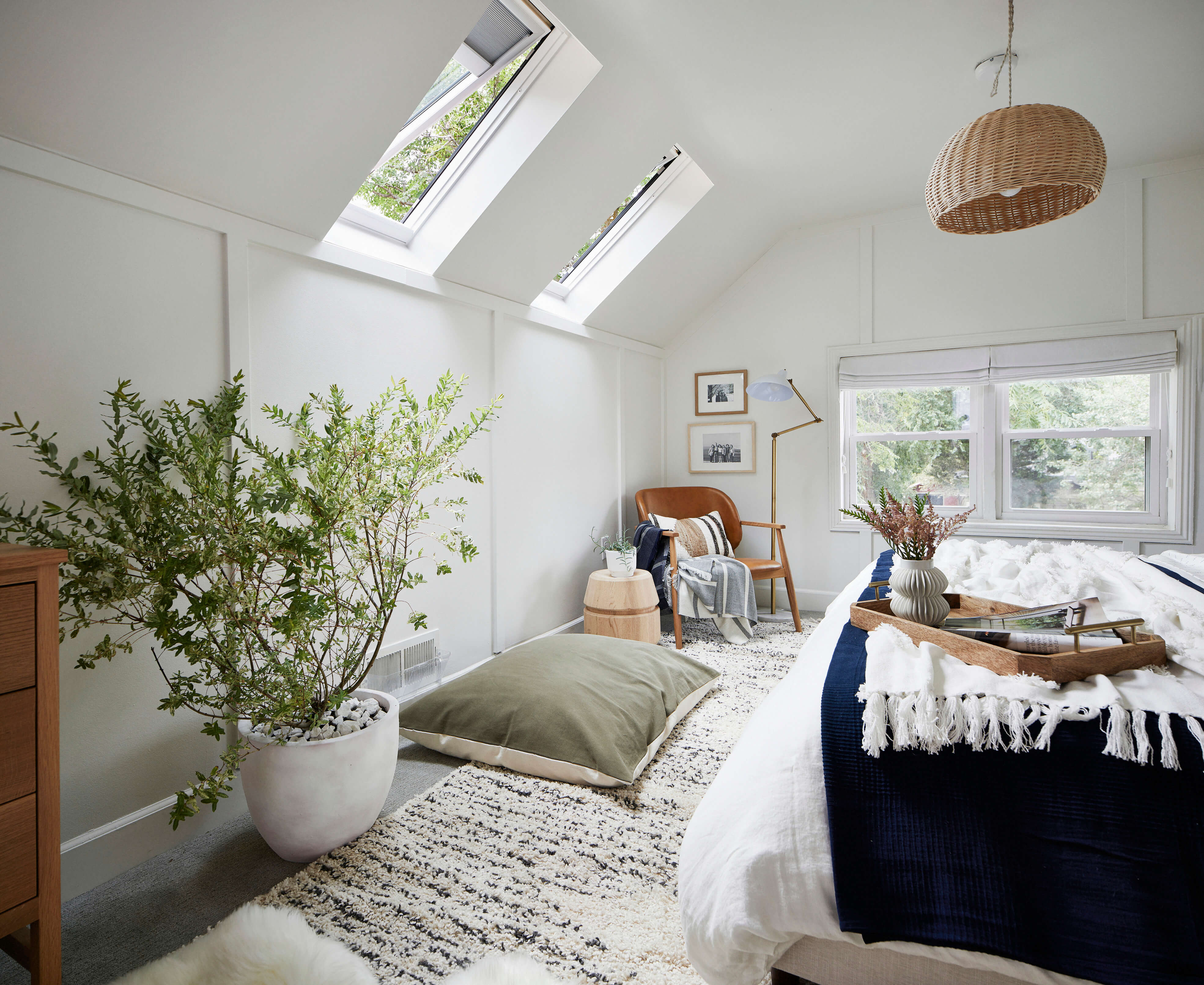 Gemütliches Schlafzimmer mit VELUX Dachflächenfenstern, moderner Einrichtung und einer grünen Pflanze.