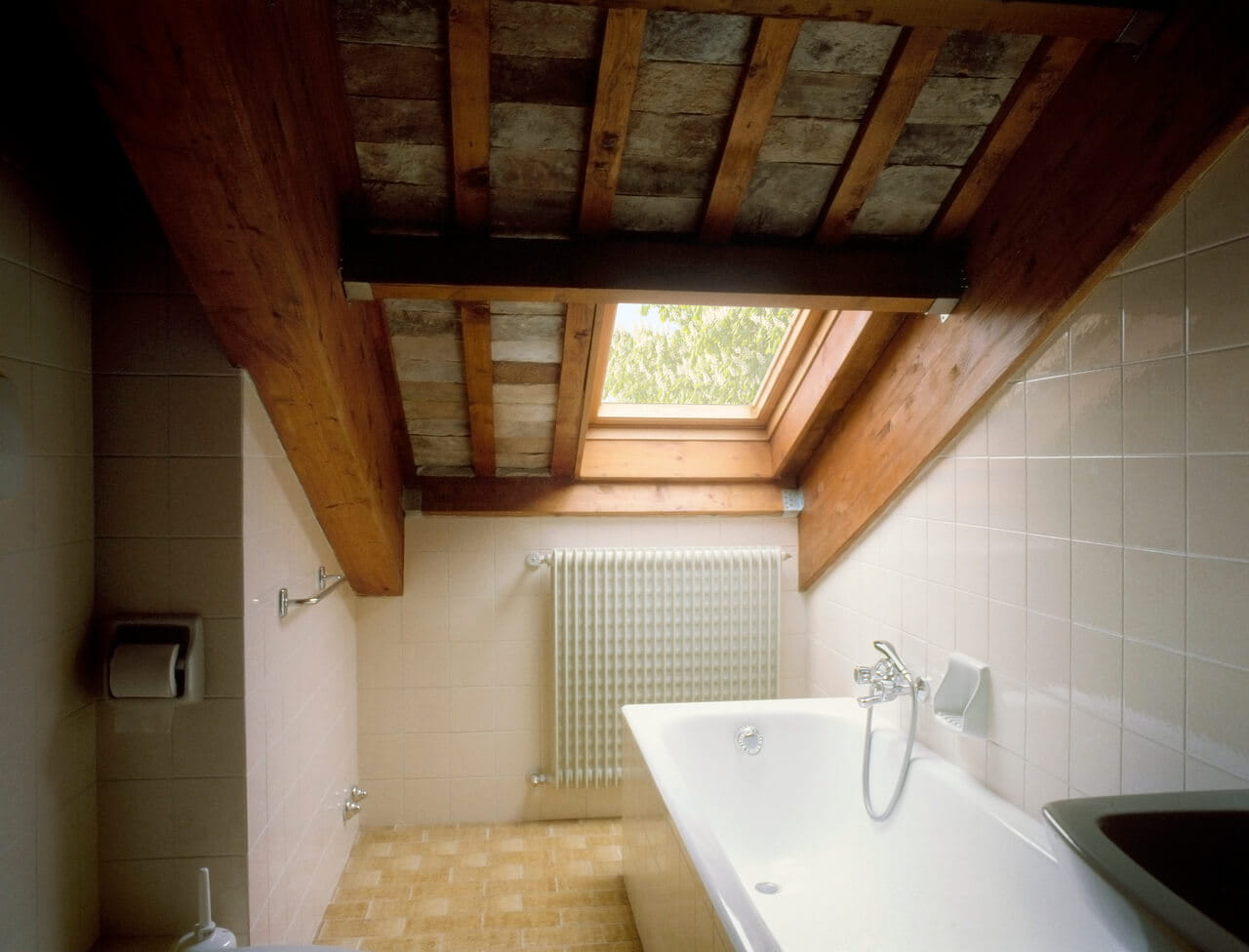 Rustisches Badezimmer mit freiliegenden Balken und einem VELUX Dachflächenfenster, das für natürliches Licht sorgt.