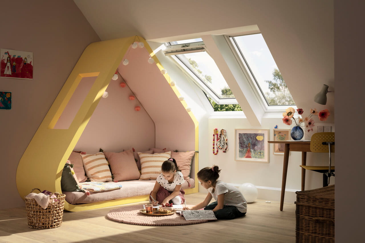 Bright attic playroom with yellow nook, VELUX roof windows, and art on walls.