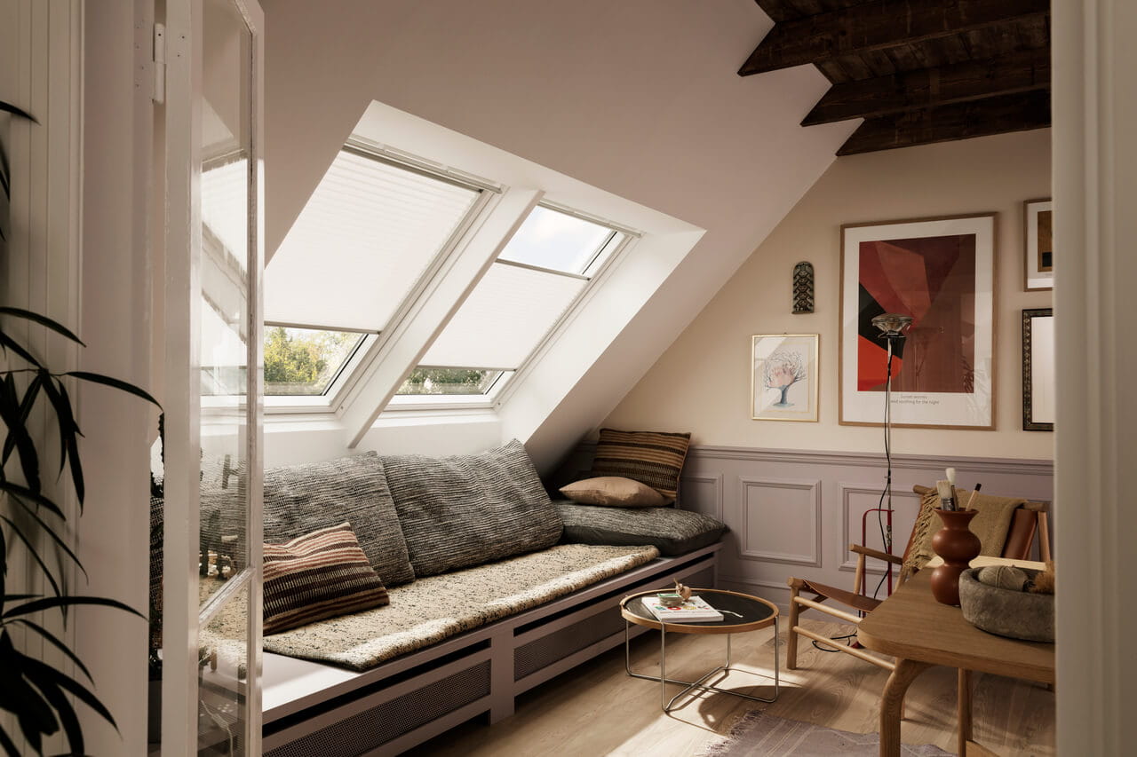 Wohnzimmer im Dachboden mit natürlichem Licht von VELUX Dachflächenfenstern, modernen Möbeln und Wandkunst.