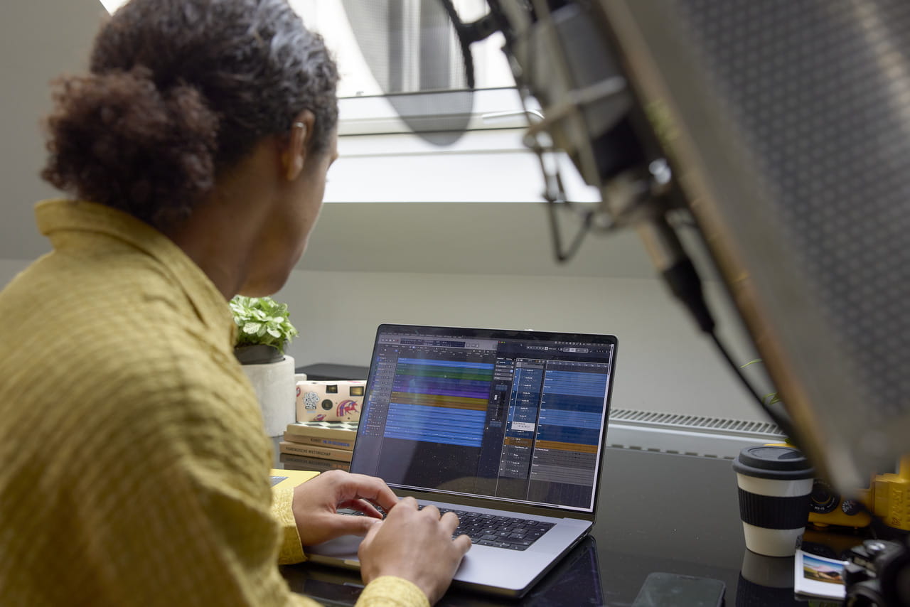 Person arbeitet an einem Laptop mit Bearbeitungssoftware in einem hellen Home-Office mit einem VELUX Dachflächenfenster.
