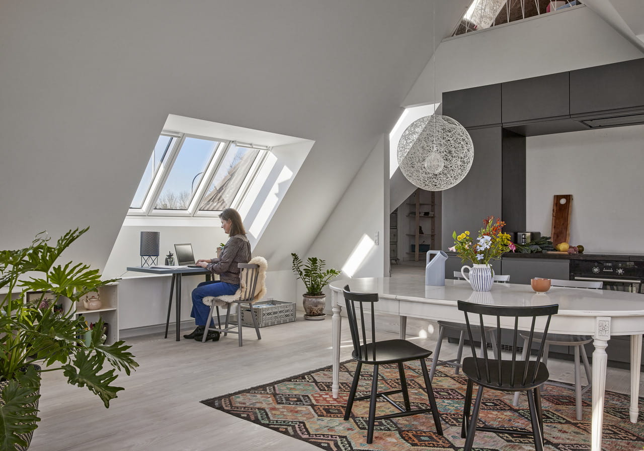 Homeoffice im Dachboden mit VELUX-Fenster, moderner Küche und dekorativer Beleuchtung.