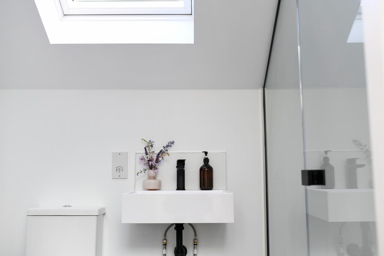 A bathroom sink with a roof window just above it.